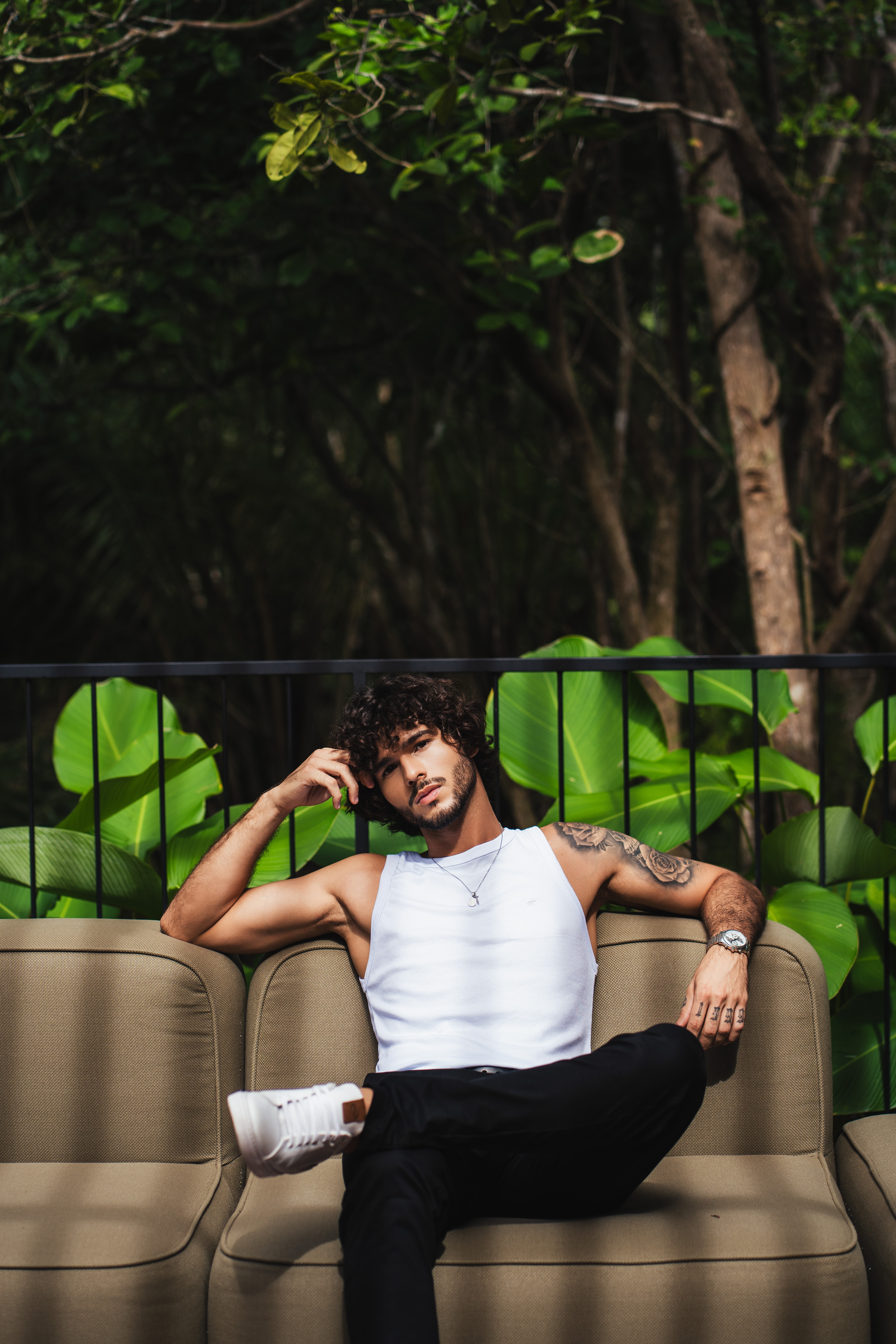 Modelo em look casual sentado em sofa externo